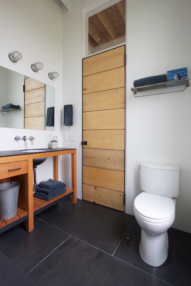 Cette photo montre une petite salle de bain principale bord de mer en bois brun avec un lavabo encastré, un placard sans porte, WC séparés, un carrelage blanc, un mur blanc et un sol en ardoise.