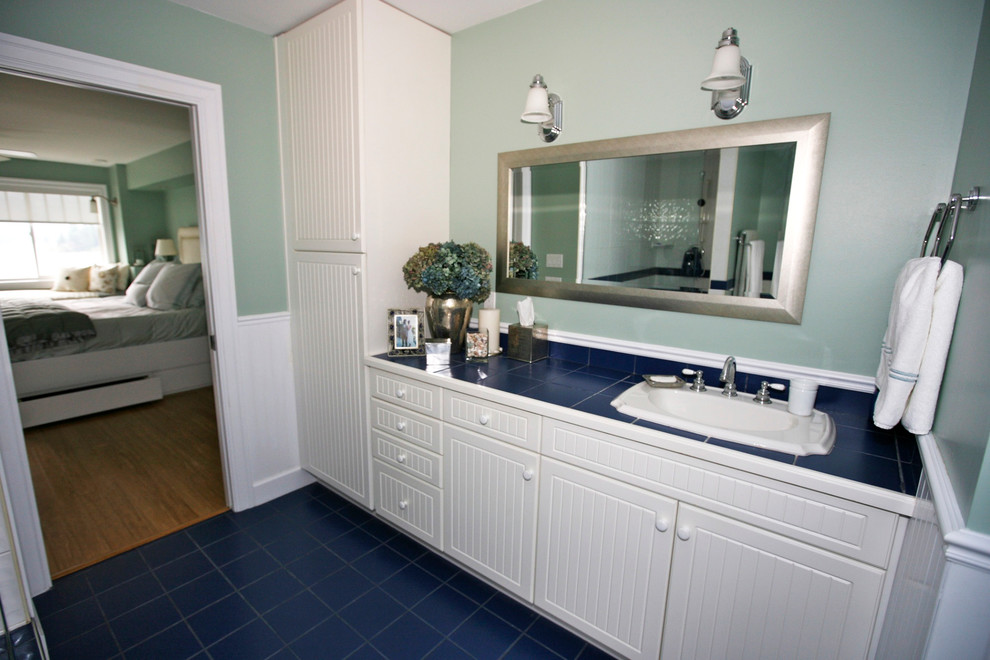 Photo of a large coastal ensuite bathroom in Vancouver with a built-in sink, recessed-panel cabinets, white cabinets, tiled worktops, a built-in bath, a corner shower, a two-piece toilet, blue tiles, porcelain tiles, blue walls and porcelain flooring.