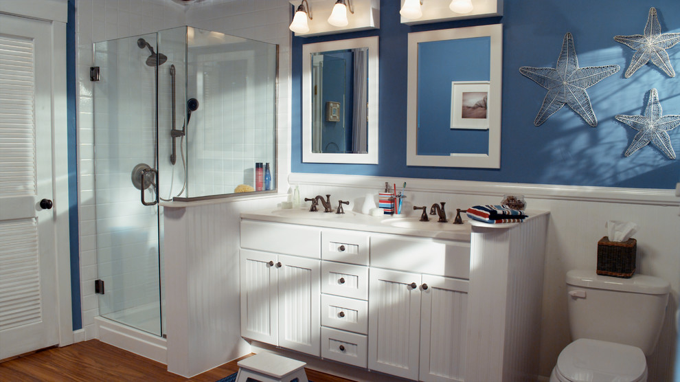 Photo of a medium sized world-inspired ensuite bathroom in Austin with an integrated sink, beaded cabinets, white cabinets, solid surface worktops, an alcove shower, a two-piece toilet, blue walls and medium hardwood flooring.