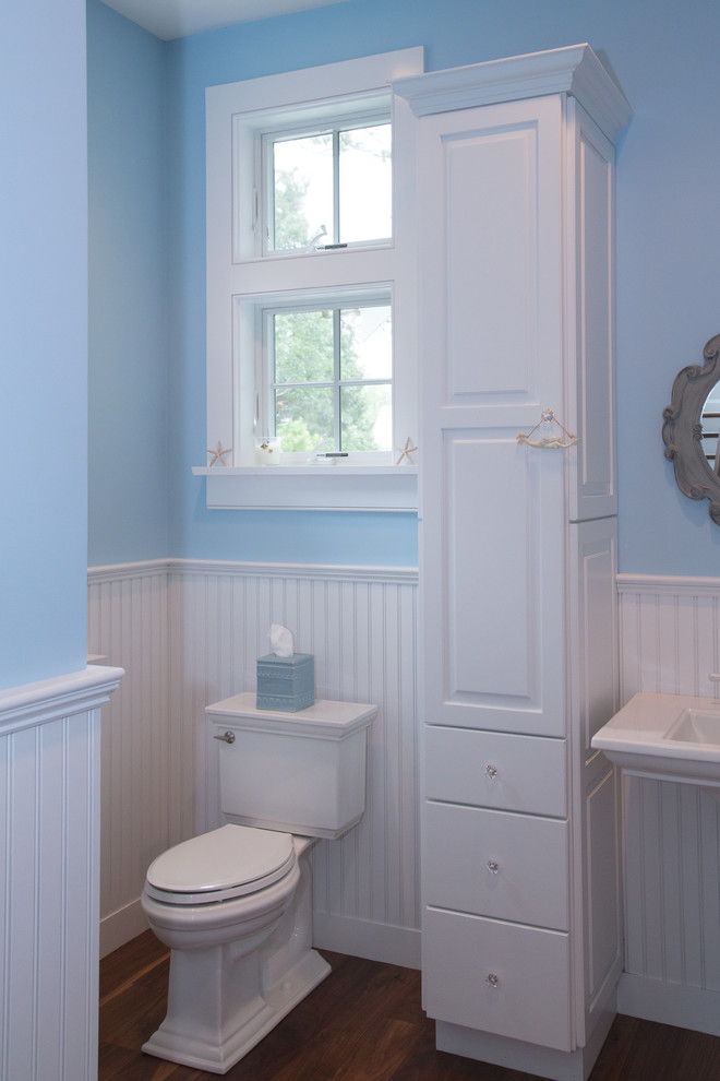 Ispirazione per una stanza da bagno stile marino di medie dimensioni con lavabo a colonna, ante con bugna sagomata, ante bianche, WC a due pezzi, pareti blu e parquet scuro