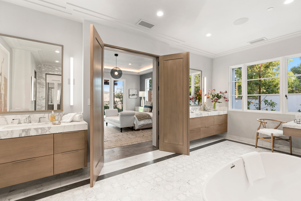 Réalisation d'une salle de bain design en bois brun avec un placard à porte plane, une baignoire indépendante, un mur gris, un lavabo encastré, un sol blanc et un plan de toilette blanc.