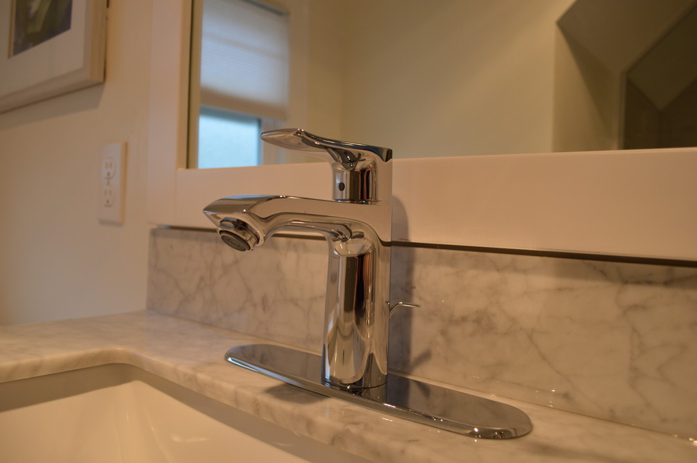 Modern inredning av ett badrum med dusch, med marmorbänkskiva, keramikplattor, klinkergolv i keramik, ett undermonterad handfat, möbel-liknande, vita skåp, en dusch i en alkov och grå kakel