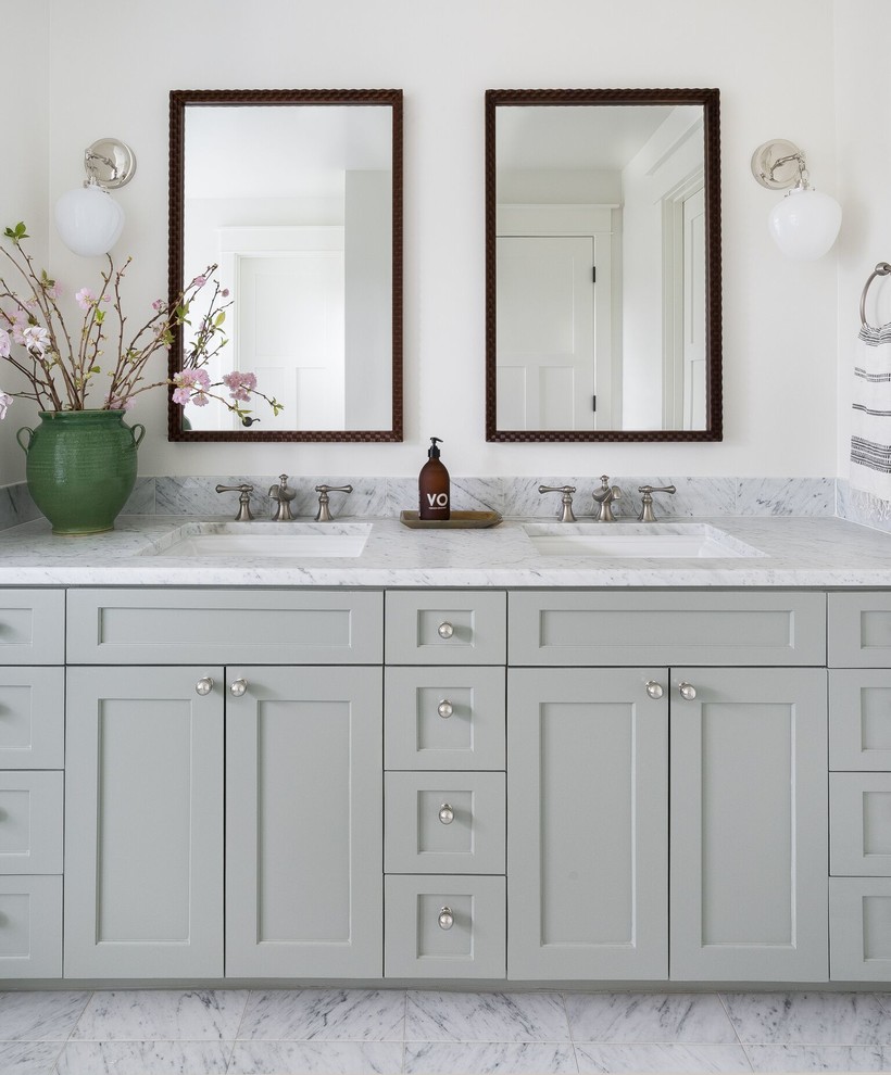 Cette photo montre une salle de bain chic avec un placard avec porte à panneau encastré, des portes de placard grises, un mur blanc, un lavabo encastré, un sol blanc et un plan de toilette blanc.