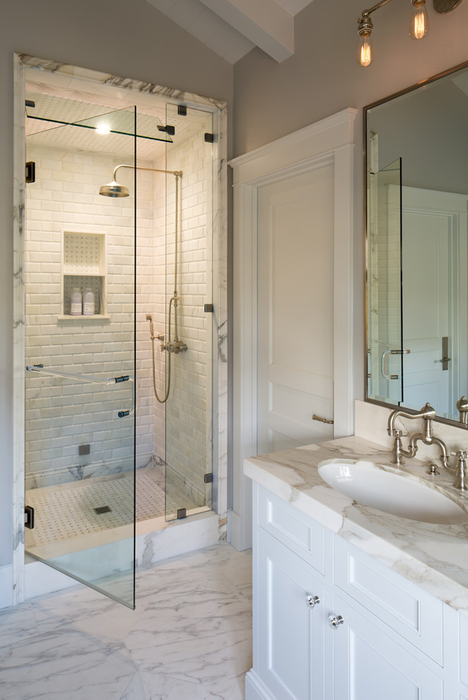 Пример оригинального дизайна: главная ванная комната среднего размера в стиле неоклассика (современная классика) с врезной раковиной, фасадами с утопленной филенкой, белыми фасадами, мраморной столешницей, отдельно стоящей ванной, душем в нише, унитазом-моноблоком, серыми стенами, мраморным полом, белой плиткой и каменной плиткой