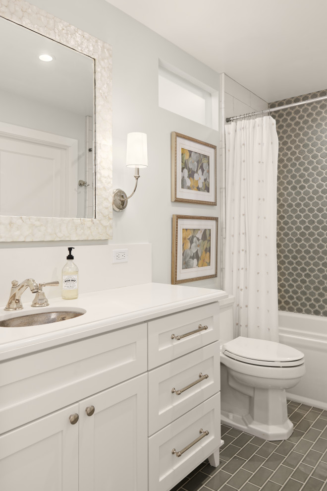 Inredning av ett maritimt mellanstort vit vitt en-suite badrum, med skåp i shakerstil, vita skåp, ett badkar i en alkov, en dusch/badkar-kombination, en toalettstol med separat cisternkåpa, grå kakel, grå väggar, klinkergolv i porslin, ett undermonterad handfat, bänkskiva i kvarts, grått golv och dusch med duschdraperi