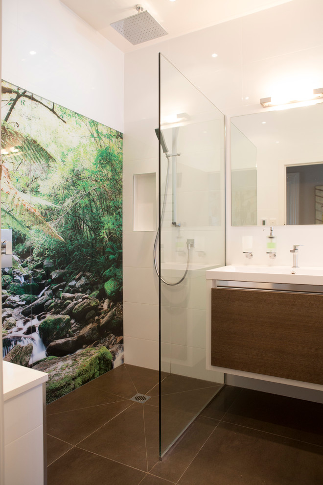 Design ideas for a medium sized family bathroom in Auckland with flat-panel cabinets, medium wood cabinets, a built-in bath, a walk-in shower, a wall mounted toilet, white tiles, cement tiles, white walls, ceramic flooring, an integrated sink and solid surface worktops.