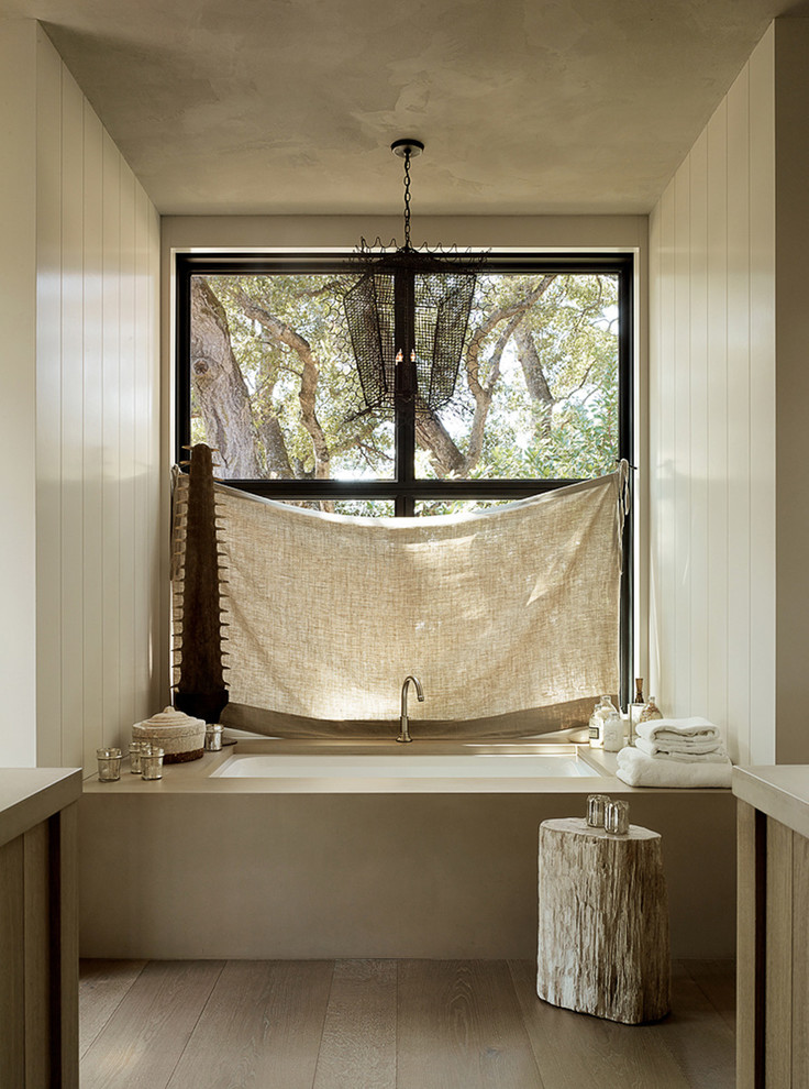 Idée de décoration pour une salle de bain principale chalet de taille moyenne avec une baignoire en alcôve, un mur beige et un sol en bois brun.
