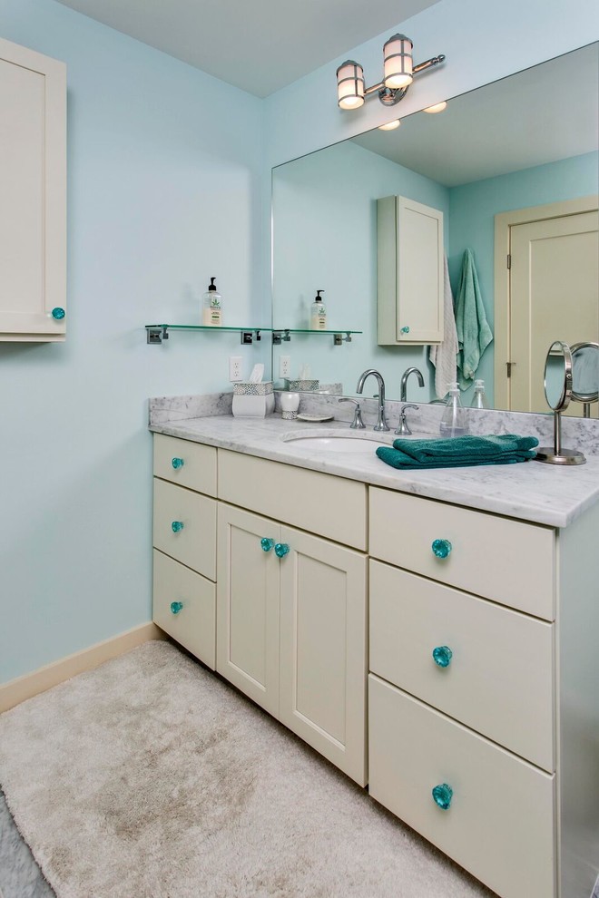 Cette photo montre une petite salle de bain bord de mer avec un placard à porte shaker, des portes de placard blanches, WC à poser, un carrelage noir et blanc, un carrelage gris, un carrelage de pierre, un mur bleu, un sol en marbre, un lavabo encastré et un plan de toilette en marbre.