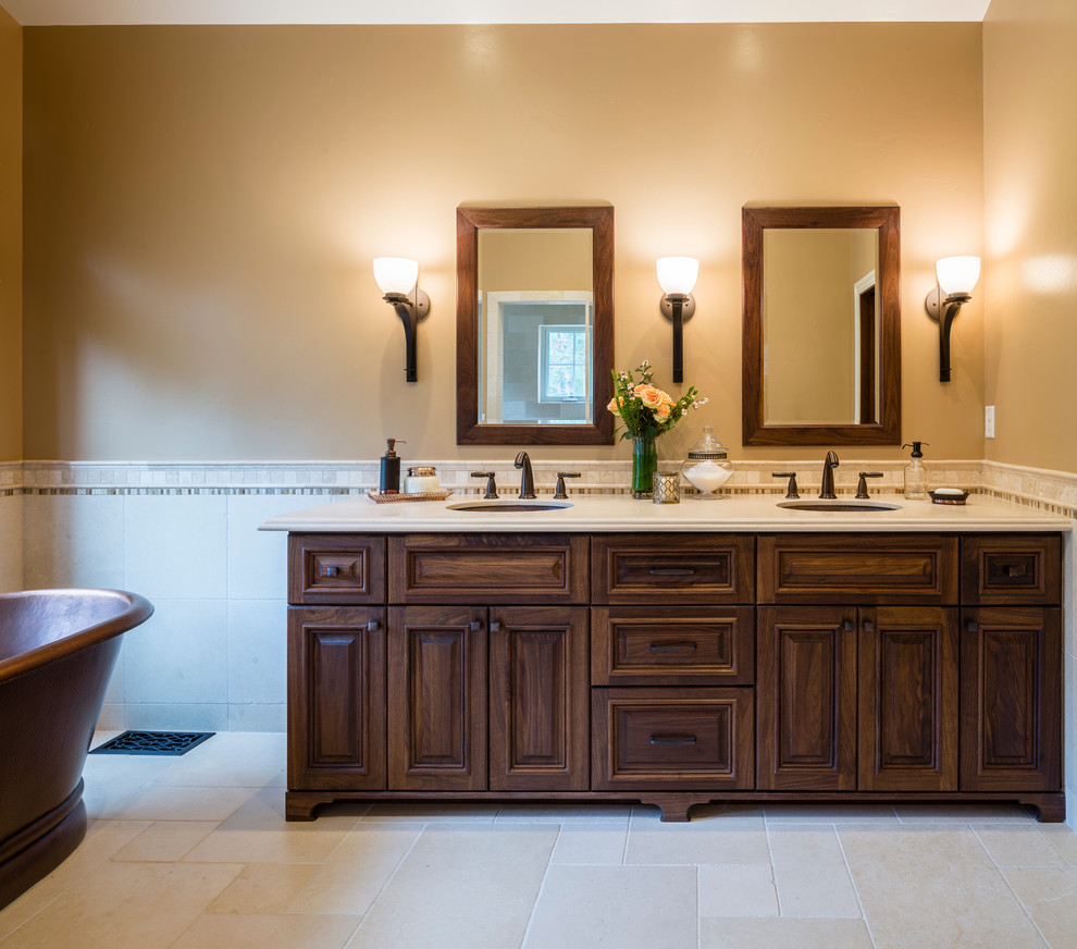 Inspiration for a mid-sized timeless master beige tile and stone tile limestone floor bathroom remodel in San Francisco with an undermount sink, furniture-like cabinets, dark wood cabinets, limestone countertops, a one-piece toilet and beige walls