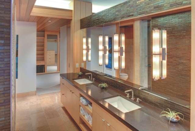 Modelo de cuarto de baño principal moderno grande con armarios con paneles lisos, puertas de armario de madera clara, paredes beige, suelo de travertino, lavabo bajoencimera y encimera de acrílico