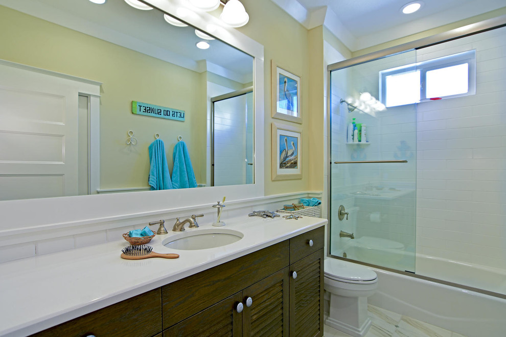 Photo of a large beach style ensuite bathroom in Tampa with a submerged sink, flat-panel cabinets, dark wood cabinets, a shower/bath combination, a one-piece toilet, white tiles, ceramic tiles and beige walls.