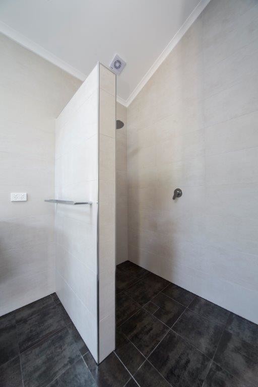 Idéer för ett stort modernt en-suite badrum, med släta luckor, skåp i mörkt trä, en öppen dusch, en toalettstol med separat cisternkåpa, beige kakel, travertinkakel, vita väggar, travertin golv, ett integrerad handfat, svart golv och med dusch som är öppen