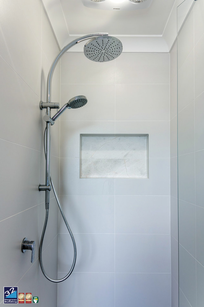 Idées déco pour une grande douche en alcôve principale moderne avec des portes de placard blanches, une baignoire indépendante, WC à poser, un carrelage gris, des carreaux de porcelaine, un mur blanc, un sol en carrelage de porcelaine, un lavabo encastré, un plan de toilette en quartz, un sol gris, une cabine de douche à porte battante et un plan de toilette blanc.