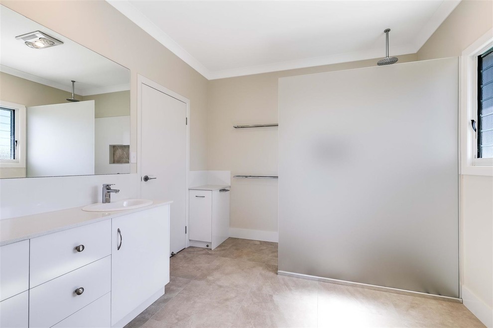 Mid-sized minimalist 3/4 white tile and ceramic tile ceramic tile and brown floor bathroom photo in Other with flat-panel cabinets, white cabinets, beige walls, a drop-in sink, solid surface countertops and white countertops