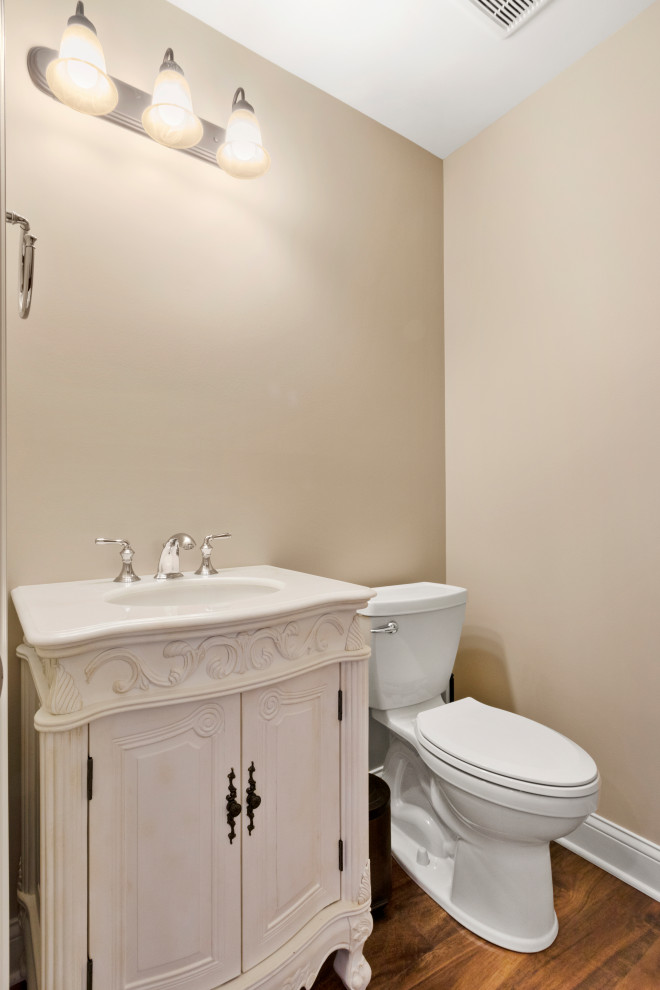 Immagine di un'ampia stanza da bagno tradizionale con ante beige, WC monopezzo, piastrelle beige, pareti beige, pavimento in vinile, lavabo integrato, pavimento marrone, top bianco, un lavabo e mobile bagno freestanding