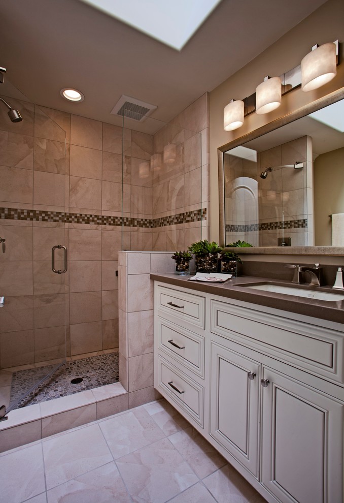 Inspiration for a mid-sized coastal 3/4 beige tile and stone tile limestone floor bathroom remodel in Orange County with an undermount sink, raised-panel cabinets, white cabinets, a one-piece toilet, beige walls and solid surface countertops