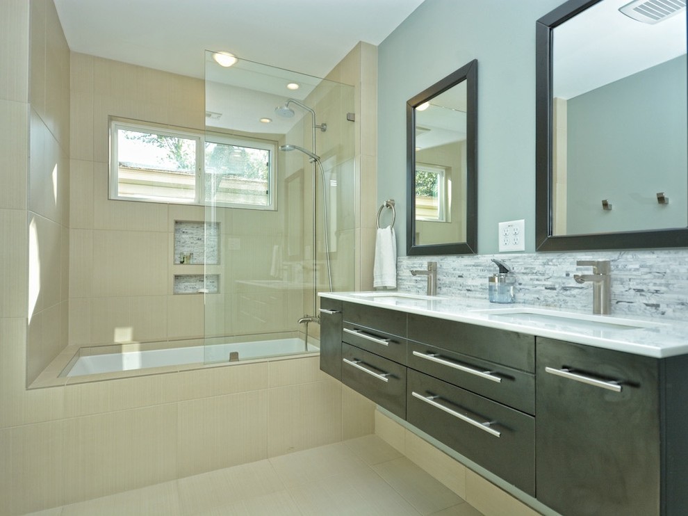 Cette image montre une salle de bain design de taille moyenne avec un lavabo posé, un placard à porte plane, des portes de placard noires, une baignoire encastrée et un combiné douche/baignoire.