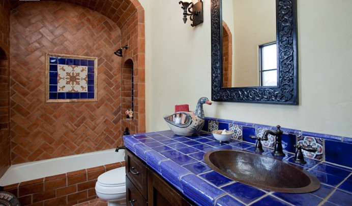 Aménagement d'une salle de bain méditerranéenne en bois foncé de taille moyenne pour enfant avec un lavabo posé, une baignoire en alcôve, un combiné douche/baignoire, un carrelage bleu et des carreaux de céramique.
