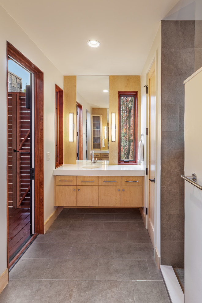 Alcove shower - large rustic master gray tile and porcelain tile porcelain tile and gray floor alcove shower idea in Other with flat-panel cabinets, light wood cabinets, beige walls, an undermount sink, solid surface countertops and a hinged shower door
