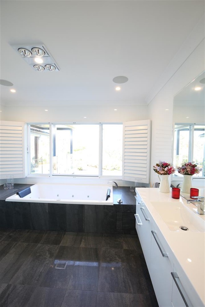 Inspiration for a mid-sized contemporary master white tile and porcelain tile travertine floor and black floor bathroom remodel in Sydney with flat-panel cabinets, white cabinets, a hot tub, a drop-in sink and quartz countertops