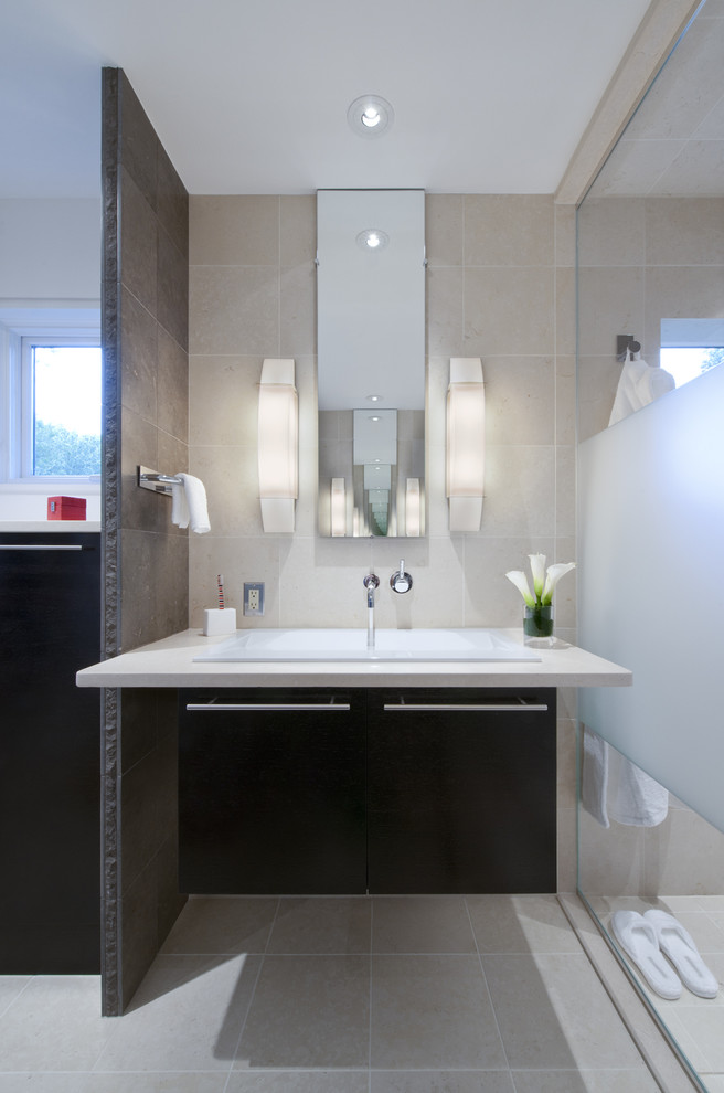 Modernes Badezimmer mit Einbauwaschbecken, flächenbündigen Schrankfronten, dunklen Holzschränken, beigen Fliesen und weißer Waschtischplatte in Washington, D.C.