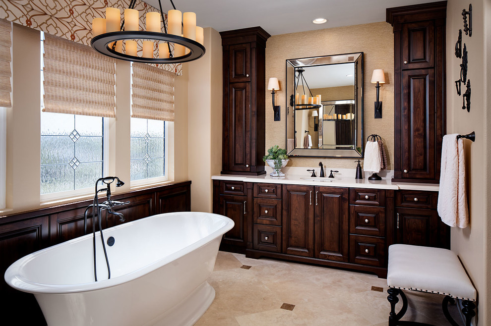 Medium sized classic ensuite bathroom in San Diego with dark wood cabinets, a freestanding bath, travertine flooring, raised-panel cabinets, a submerged sink and beige walls.