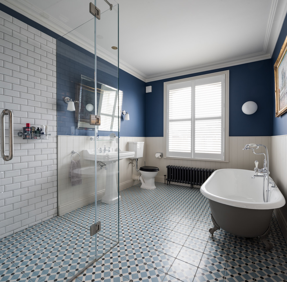Пример оригинального дизайна: главная ванная комната в классическом стиле с ванной на ножках, угловым душем, раздельным унитазом, белой плиткой, плиткой кабанчик, разноцветными стенами, раковиной с пьедесталом, синим полом и душем с распашными дверями