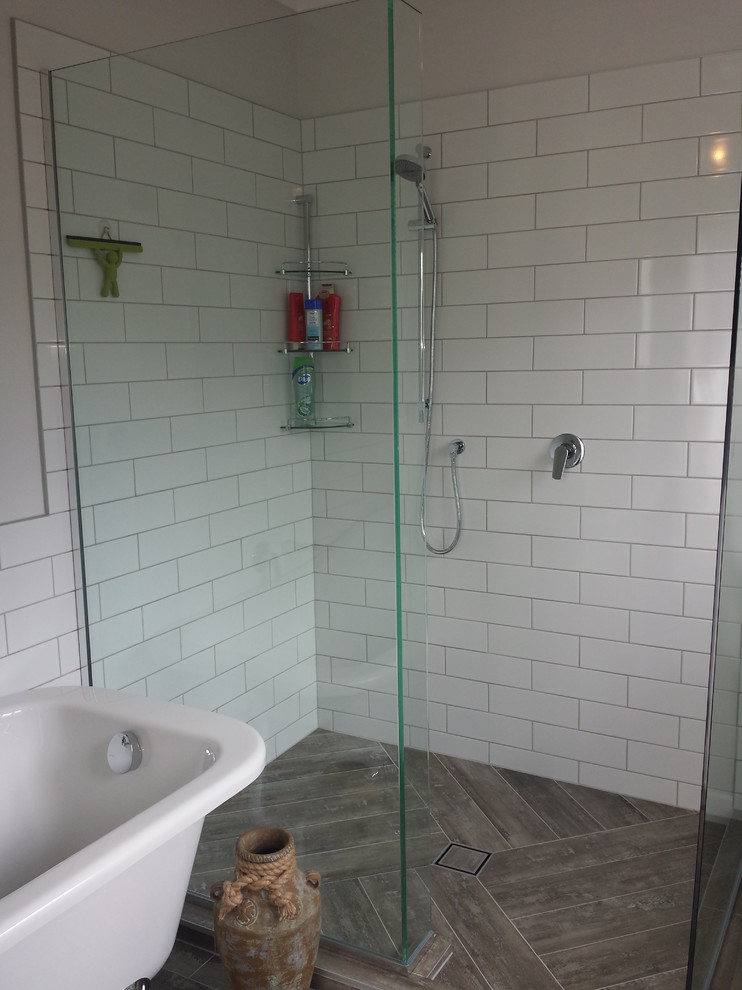 This is an example of a medium sized industrial ensuite bathroom in Auckland with flat-panel cabinets, dark wood cabinets, solid surface worktops, a claw-foot bath, a walk-in shower, brown tiles, porcelain tiles, white walls and porcelain flooring.
