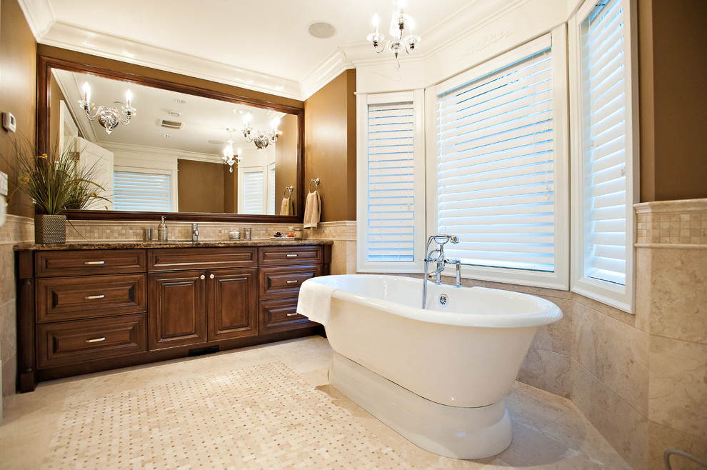Photo of a large traditional ensuite bathroom in Vancouver with raised-panel cabinets, dark wood cabinets, an alcove bath, a corner shower, a one-piece toilet, beige tiles, porcelain tiles, brown walls, porcelain flooring, a submerged sink, granite worktops, beige floors and a hinged door.