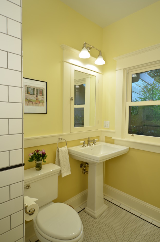 Idéer för små amerikanska badrum, med luckor med profilerade fronter, vita skåp, en toalettstol med separat cisternkåpa, svart och vit kakel, keramikplattor, gula väggar, klinkergolv i keramik och ett piedestal handfat