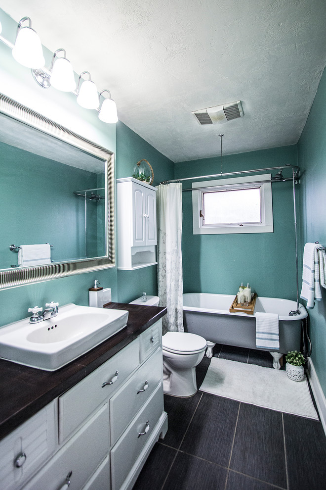 Источник вдохновения для домашнего уюта: ванная комната среднего размера в стиле модернизм с плоскими фасадами, белыми фасадами, отдельно стоящей ванной, душем над ванной, раздельным унитазом, синими стенами, полом из ламината, душевой кабиной, настольной раковиной, столешницей из ламината, черным полом, шторкой для ванной и коричневой столешницей