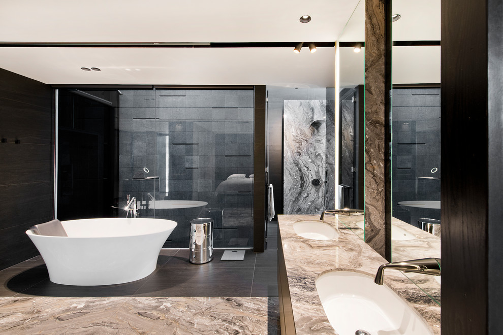 Foto på ett funkis grå en-suite badrum, med släta luckor, svarta skåp, ett fristående badkar, svart kakel, ett undermonterad handfat och flerfärgat golv