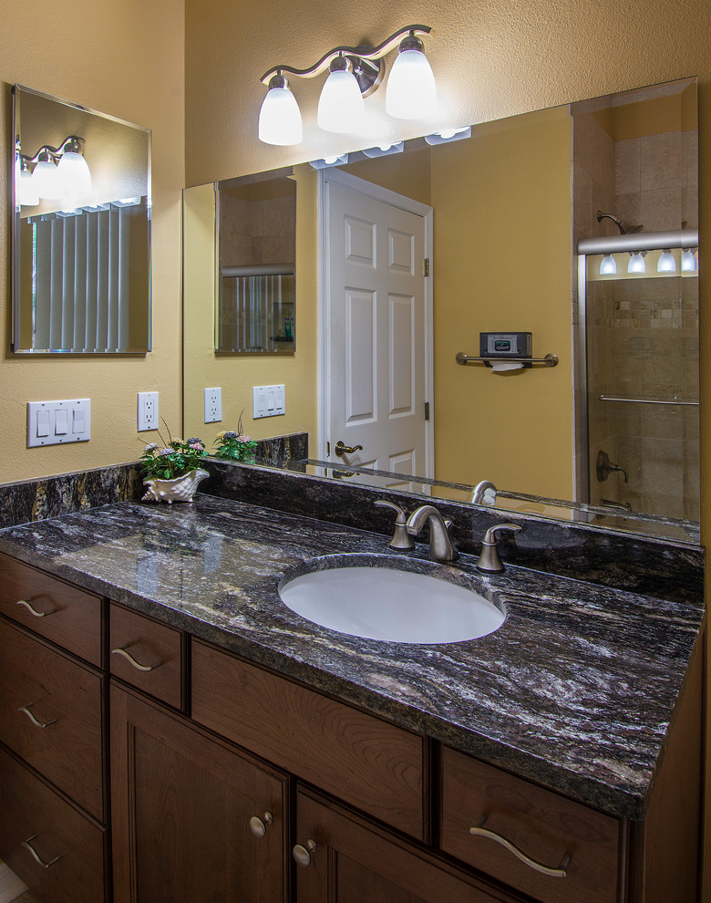 Bathroom - small traditional beige tile and stone tile travertine floor bathroom idea in Tampa with an undermount sink, shaker cabinets, medium tone wood cabinets, granite countertops, a one-piece toilet and yellow walls
