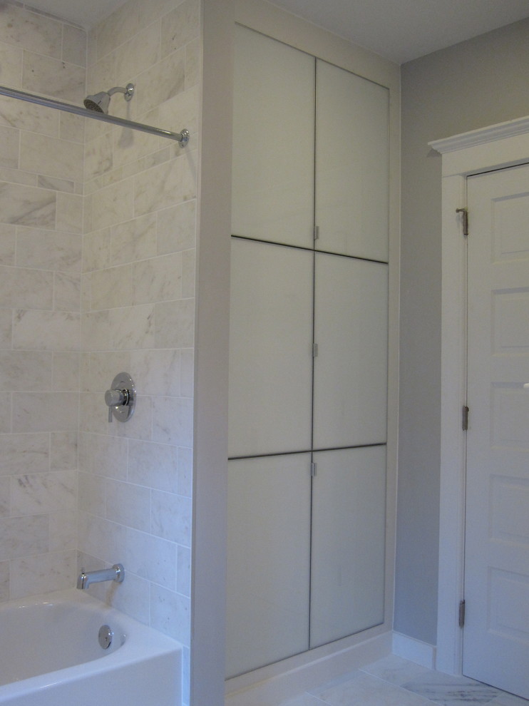 Immagine di una stanza da bagno padronale classica di medie dimensioni con ante di vetro, ante bianche, vasca ad alcova, vasca/doccia, piastrelle bianche, piastrelle in pietra, pareti grigie e pavimento in marmo