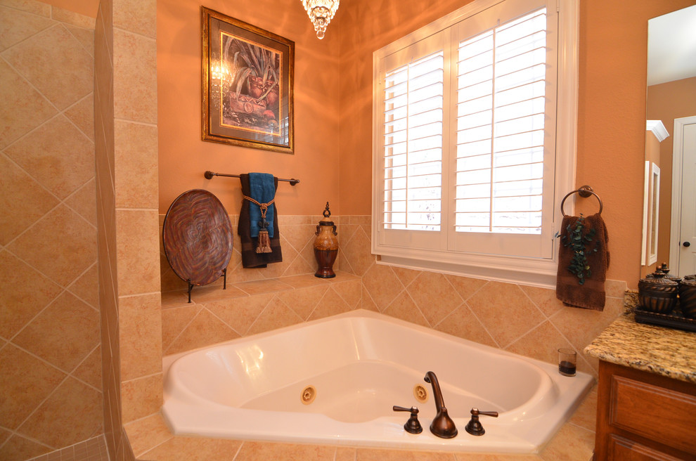Photo of a medium sized mediterranean family bathroom in Austin with a built-in sink, raised-panel cabinets, medium wood cabinets, granite worktops, a corner bath, a double shower, a two-piece toilet, beige tiles, porcelain tiles, beige walls and porcelain flooring.