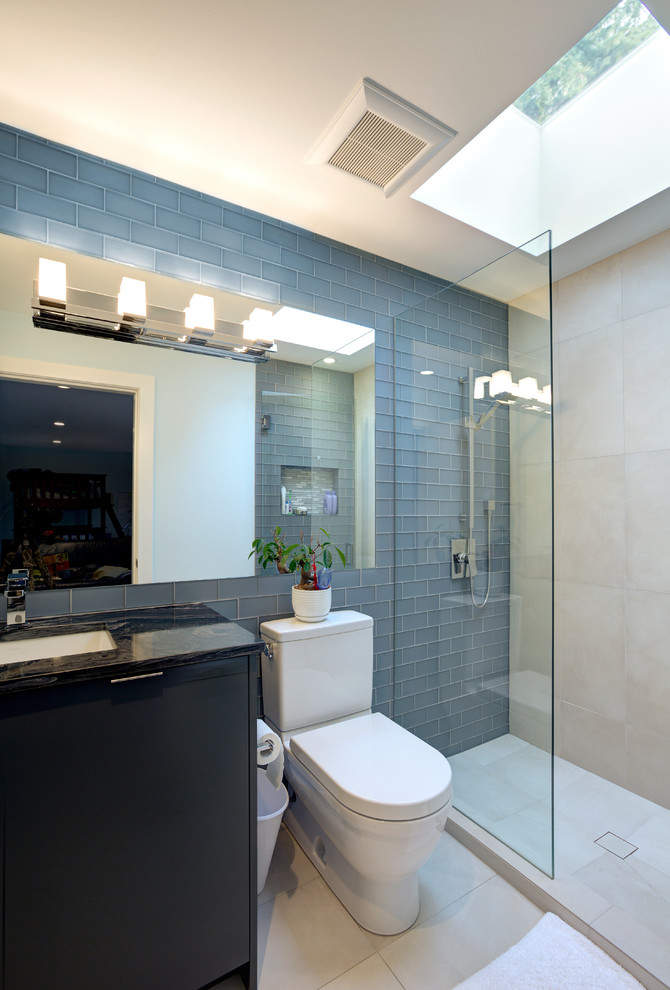 Immagine di una stanza da bagno contemporanea con lavabo sottopiano, ante lisce, ante in legno bruno, top in granito, doccia aperta, WC a due pezzi, piastrelle blu e piastrelle di vetro