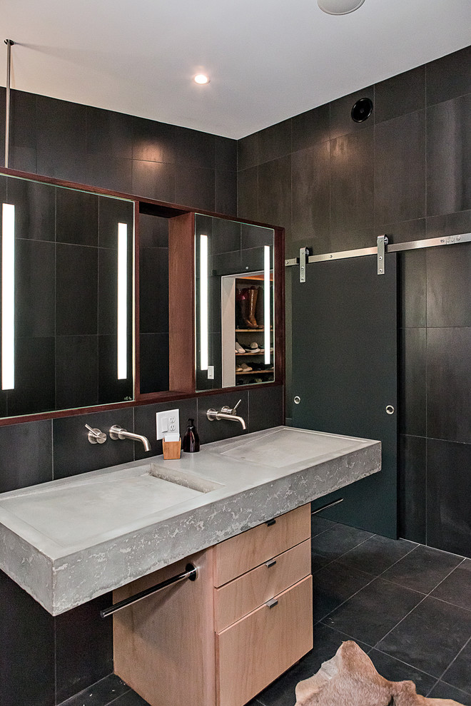 Пример оригинального дизайна: большая главная ванная комната в стиле модернизм с плоскими фасадами, светлыми деревянными фасадами, открытым душем, инсталляцией, черной плиткой, керамогранитной плиткой, черными стенами, бетонным полом, раковиной с несколькими смесителями, столешницей из бетона, серым полом, открытым душем и серой столешницей