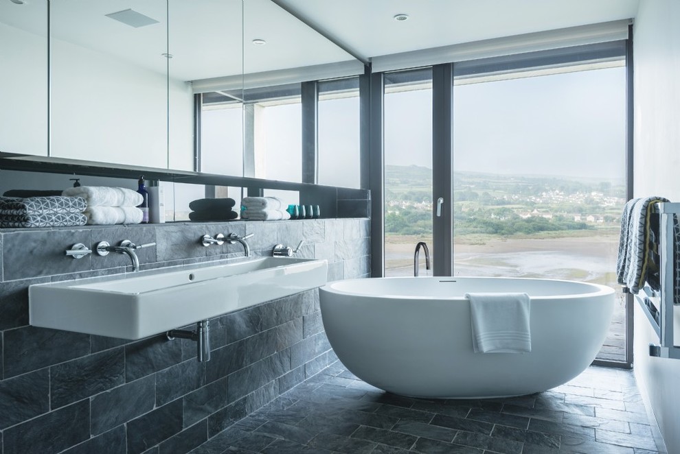 Inspiration for a medium sized contemporary bathroom in Other with a freestanding bath, black tiles, white walls, a trough sink and black floors.