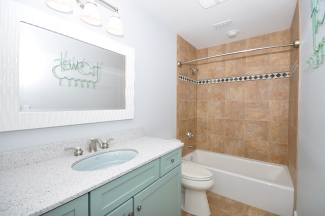 Photo of a nautical bathroom in Jacksonville with a submerged sink, recessed-panel cabinets, blue cabinets, an alcove bath, a shower/bath combination, multi-coloured tiles, blue walls and ceramic flooring.