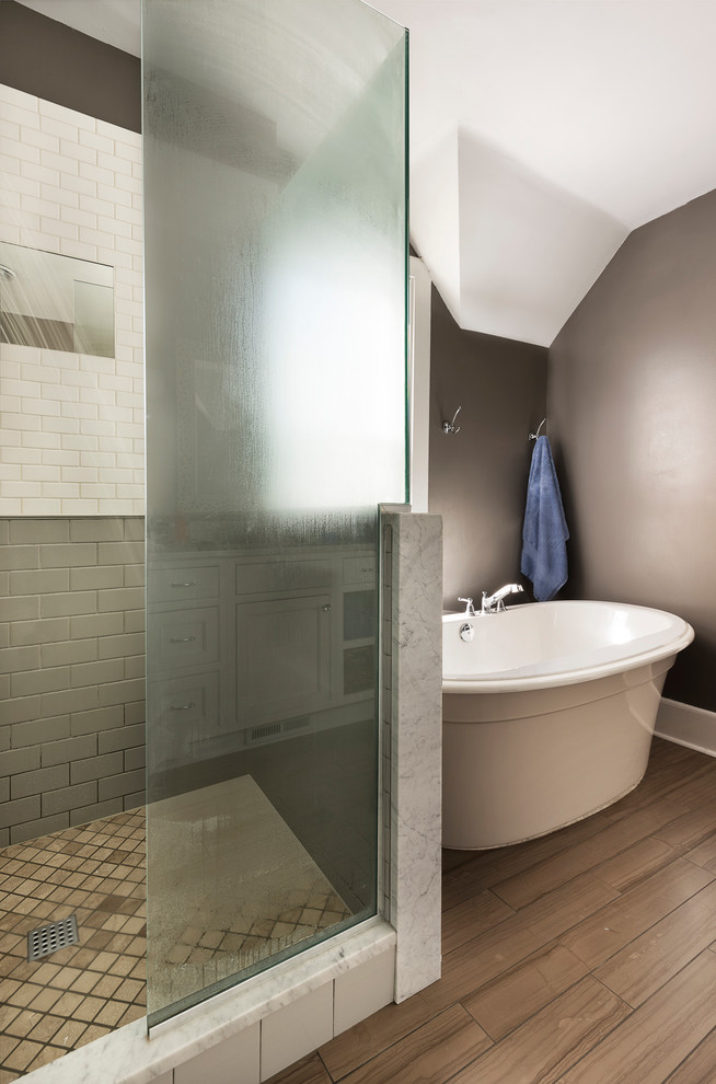 Klassisk inredning av ett en-suite badrum, med vita skåp, marmorbänkskiva, ett fristående badkar, en dusch i en alkov, vit kakel och beige väggar
