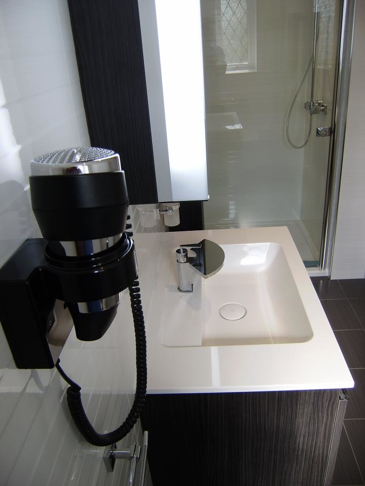 Idéer för små funkis badrum med dusch, med ett väggmonterat handfat, släta luckor, grå skåp, bänkskiva i akrylsten, ett badkar med tassar, en dusch i en alkov, en vägghängd toalettstol, vit kakel, porslinskakel, vita väggar och klinkergolv i porslin
