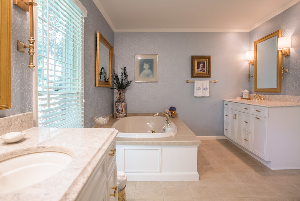 シーダーラピッズにある高級な中くらいなコンテンポラリースタイルのおしゃれなマスターバスルーム (青い壁、落し込みパネル扉のキャビネット、白いキャビネット、コーナー設置型シャワー、セラミックタイルの床、アンダーカウンター洗面器、クオーツストーンの洗面台、コーナー型浴槽、ベージュの床、造り付け洗面台、壁紙) の写真