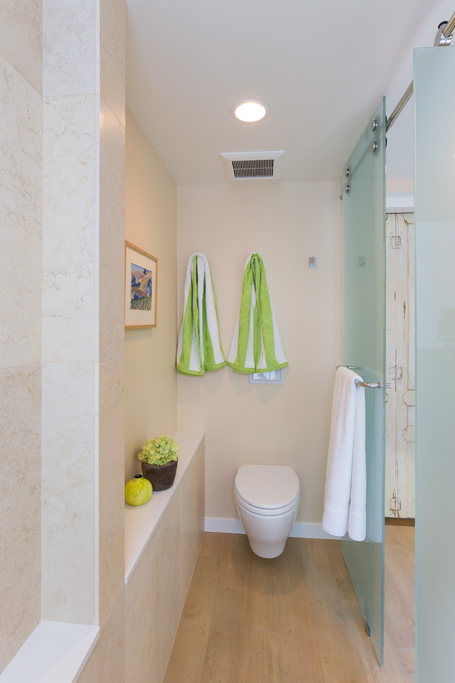 Foto de cuarto de baño pequeño con sanitario de pared, baldosas y/o azulejos beige y suelo de madera clara