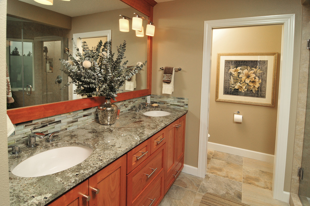 Aménagement d'une douche en alcôve craftsman en bois brun avec un lavabo encastré, un placard à porte shaker, un plan de toilette en granite, un carrelage multicolore et un mur beige.
