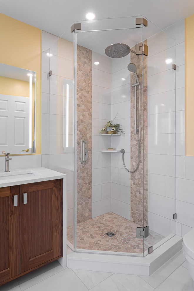 Идея дизайна: главная ванная комната среднего размера в стиле неоклассика (современная классика) с фасадами в стиле шейкер, темными деревянными фасадами, отдельно стоящей ванной, угловым душем, коричневой плиткой, белой плиткой, керамогранитной плиткой, желтыми стенами, полом из керамогранита, врезной раковиной, белым полом, душем с распашными дверями, белой столешницей, раздельным унитазом, столешницей из искусственного кварца, тумбой под две раковины и встроенной тумбой