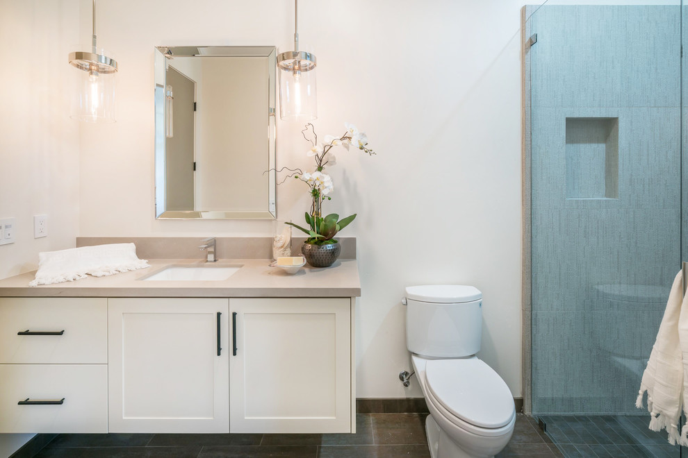 Example of a large trendy master porcelain tile and white floor bathroom design in Santa Barbara with flat-panel cabinets, medium tone wood cabinets, a one-piece toilet, white walls, an undermount sink, quartz countertops, a hinged shower door and white countertops