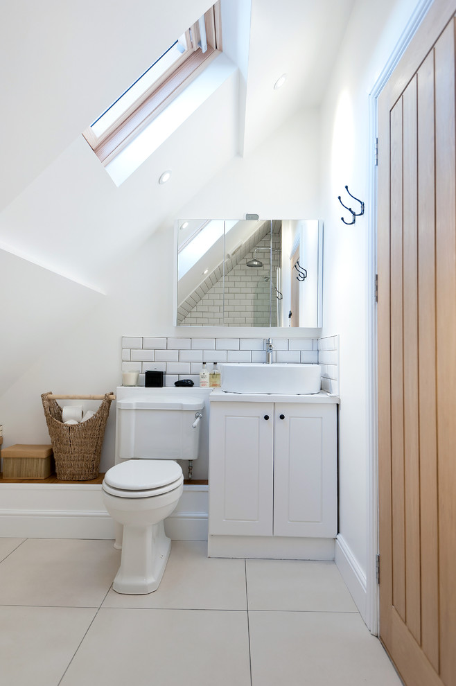 Exempel på ett lantligt badrum, med ett fristående handfat, vita skåp, en toalettstol med separat cisternkåpa, vit kakel, tunnelbanekakel och vita väggar
