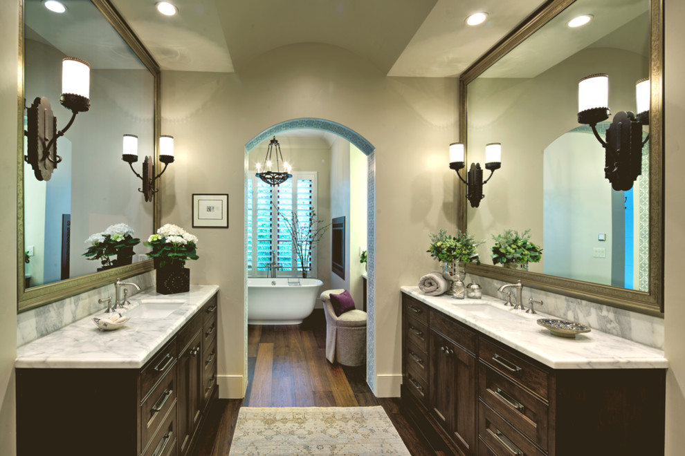 Expansive mediterranean ensuite bathroom in Sacramento with recessed-panel cabinets, dark wood cabinets, a freestanding bath, white walls, dark hardwood flooring, a submerged sink, marble worktops and brown floors.