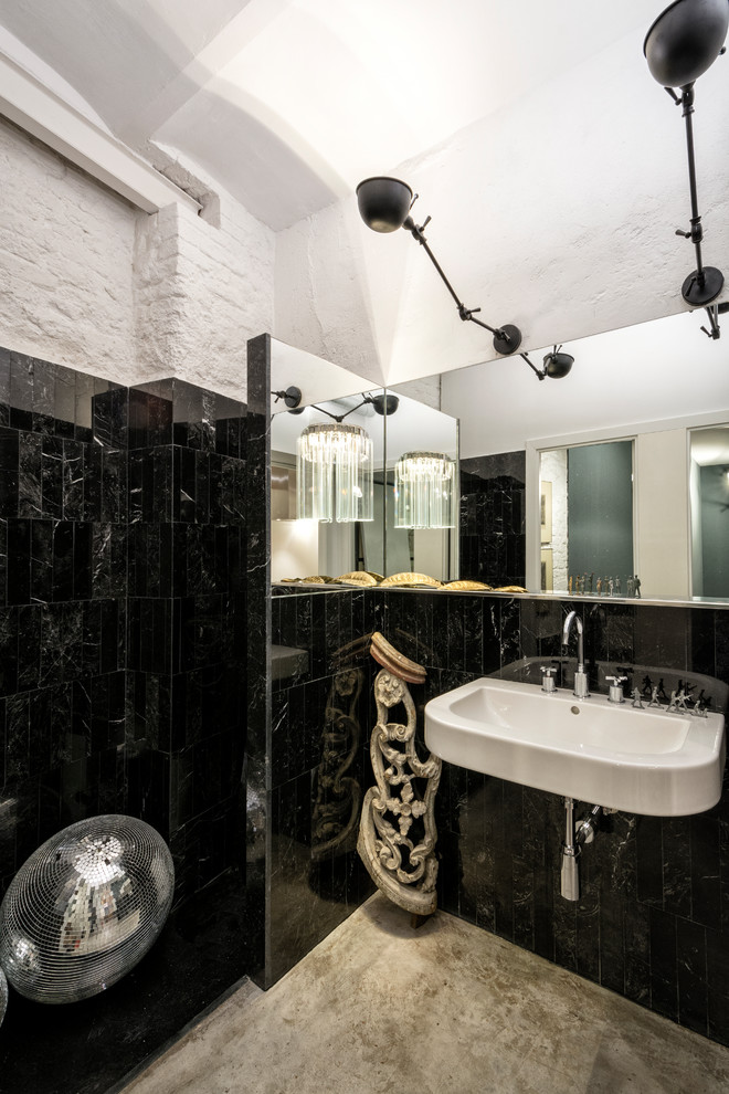 Diseño de cuarto de baño industrial con baldosas y/o azulejos negros, lavabo suspendido, paredes blancas, suelo de cemento y suelo gris