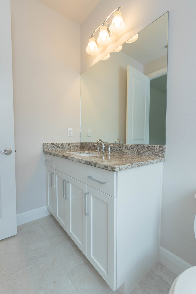 Small contemporary family bathroom in Other with shaker cabinets, white cabinets, a built-in shower, a one-piece toilet, beige walls, porcelain flooring, a submerged sink, granite worktops, beige floors and a hinged door.